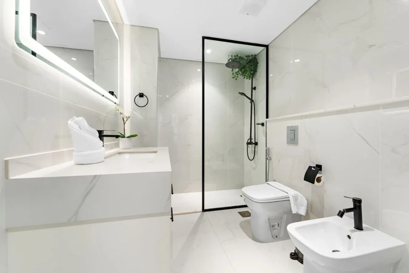 Un baño luminoso con lavabo, inodoro y ducha de vidrio.