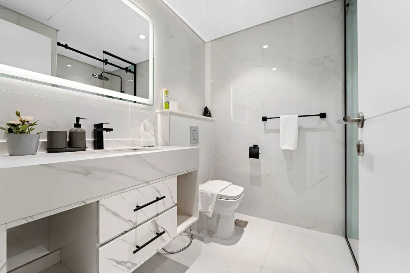 Un baño moderno y luminoso con lavabo, inodoro y ducha de vidrio.