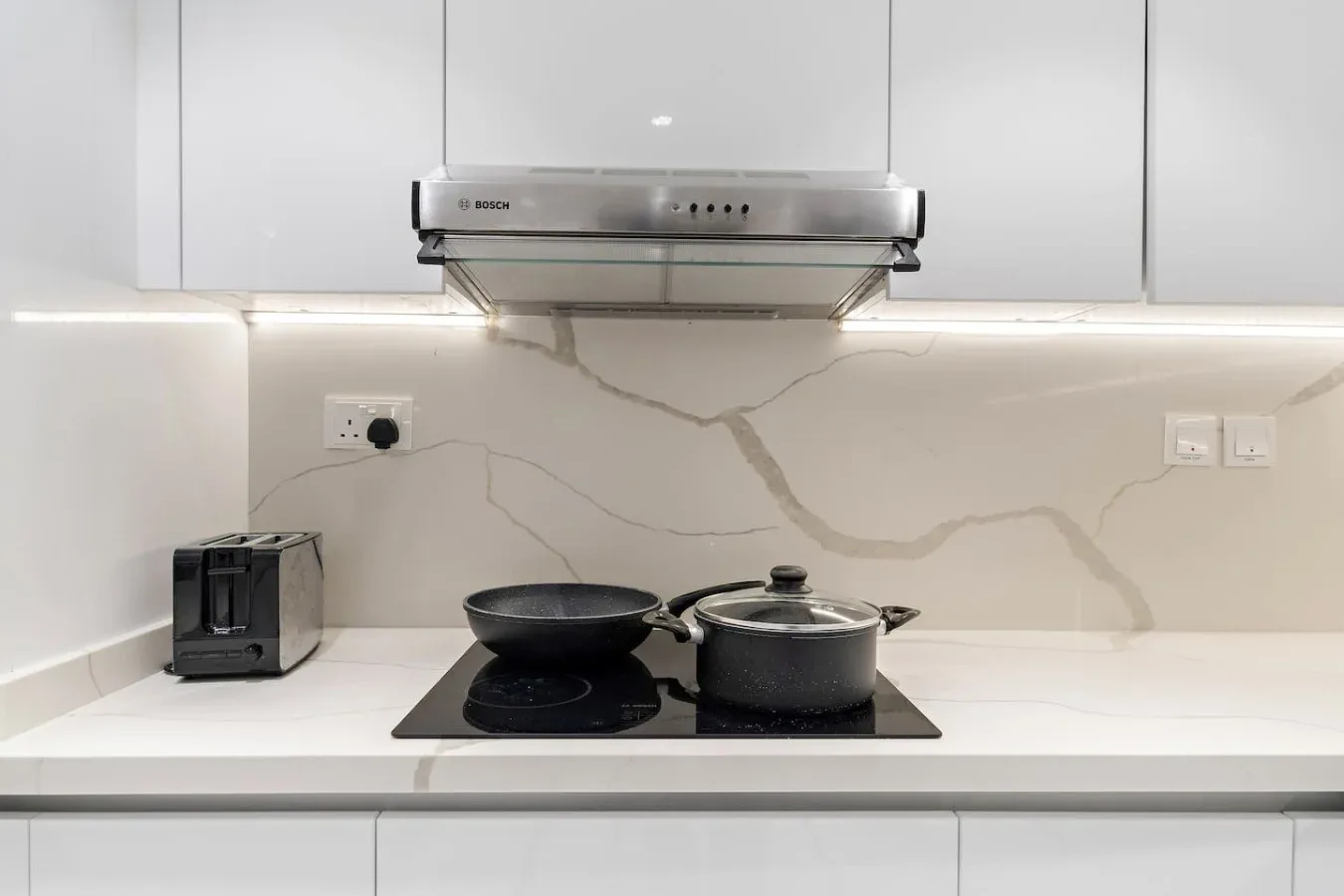 Una encimera de cocina moderna con placa de cocción y campana extractora.