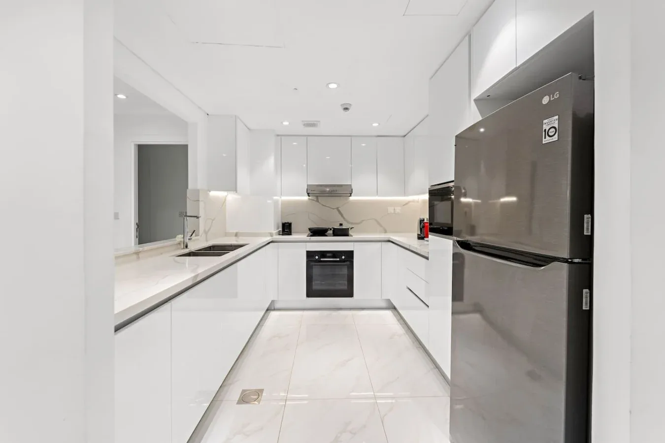Una cocina moderna y luminosa con armarios blancos y electrodomésticos de acero inoxidable.