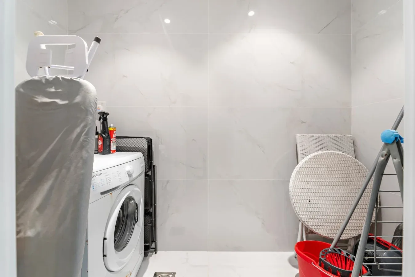 Un cuarto de lavandería alicatado con una lavadora y productos de limpieza.