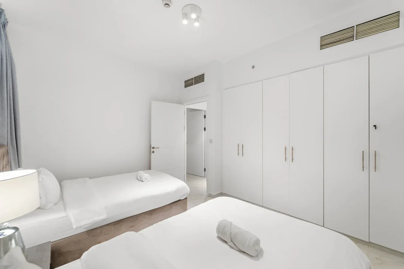 Un dormitorio luminoso con ropa de cama blanca y armarios empotrados.