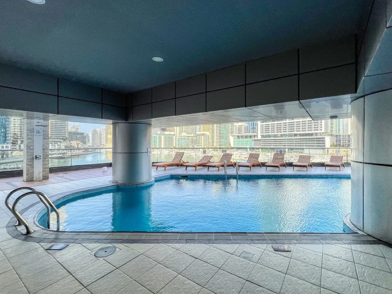 Una piscina cubierta con tumbonas junto a las ventanas.