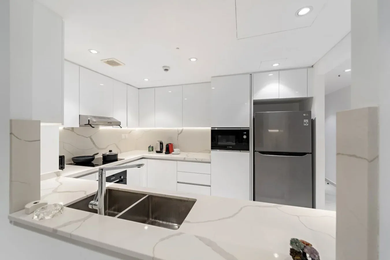 Una cocina blanca moderna con una isla grande y electrodomésticos de acero inoxidable.