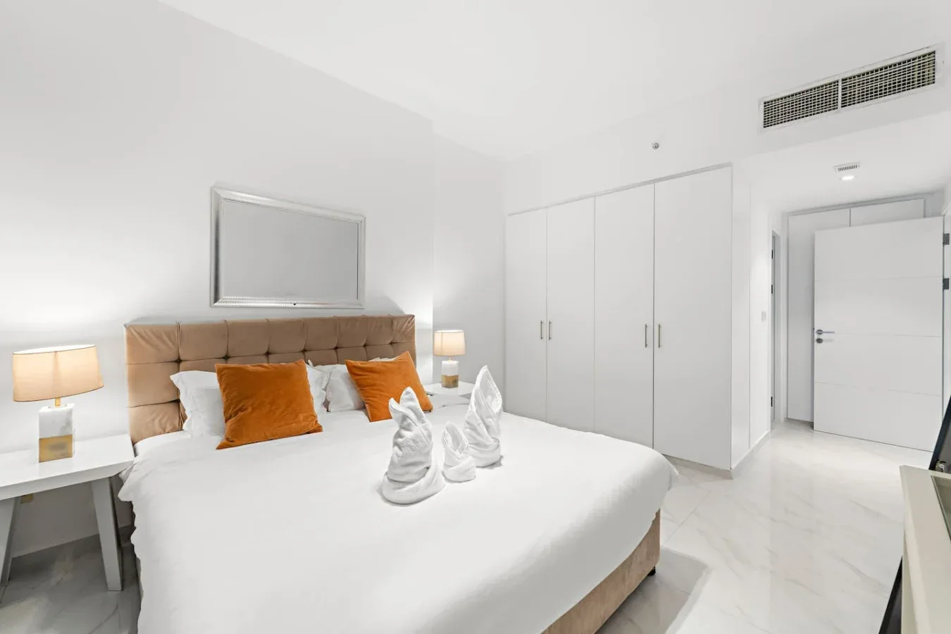Un dormitorio luminoso con una cama bien hecha y armarios empotrados.