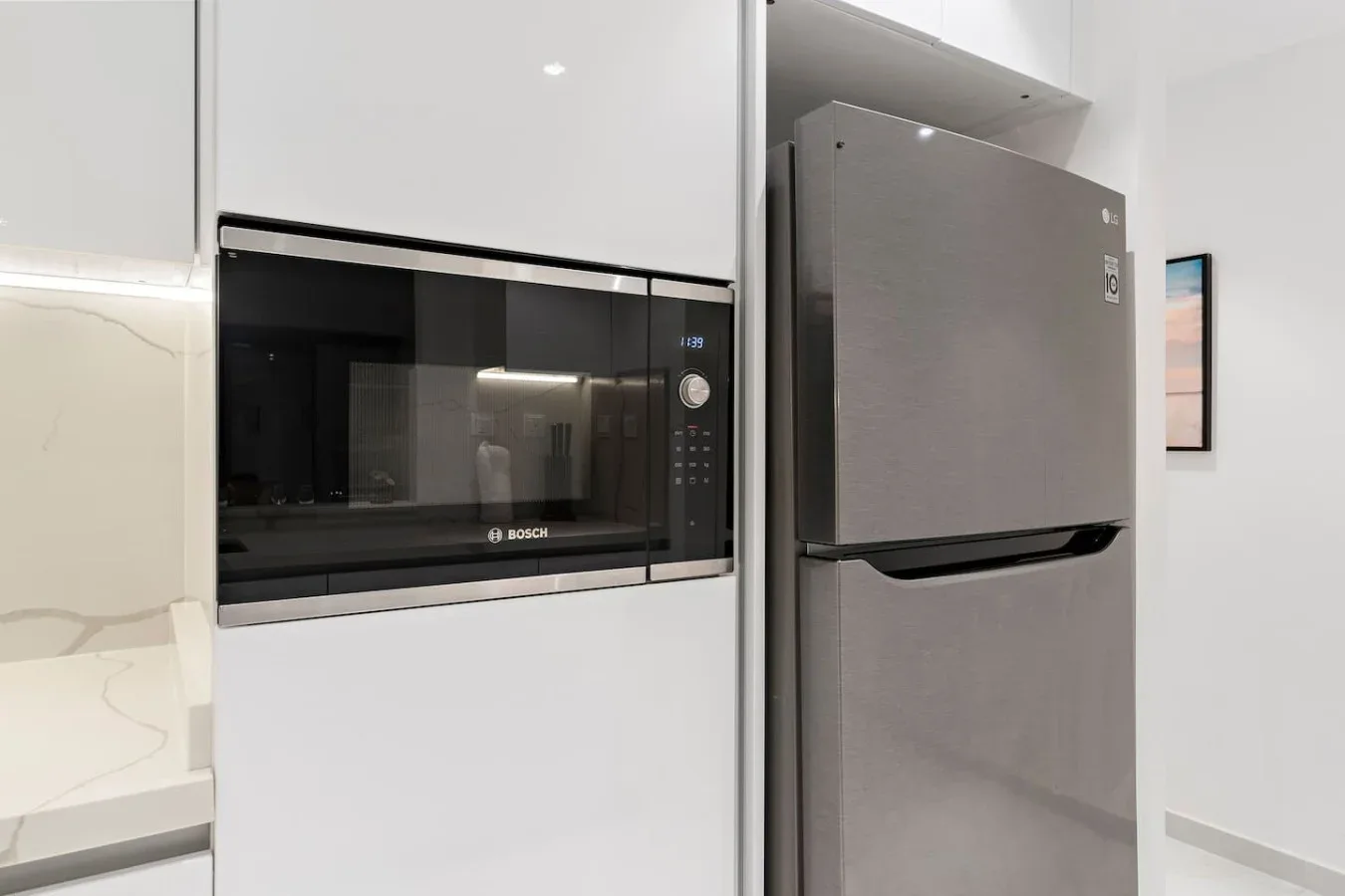 Una cocina moderna con microondas empotrado y refrigerador.