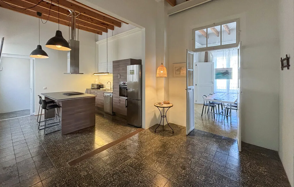 Cocina y comedor abiertos con una isla central y lámparas colgantes.