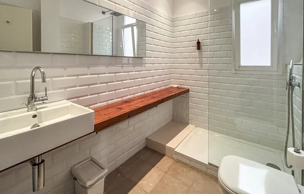 Un baño revestido de azulejos con lavabo, ducha e inodoro.