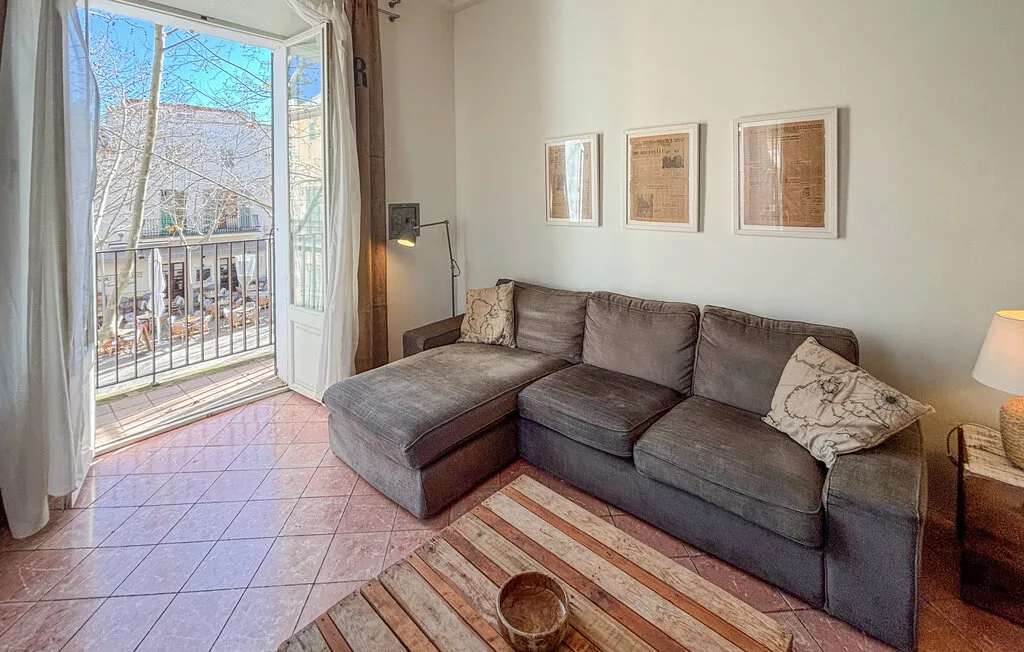 Una sala de estar con un sofá seccional junto a una ventana al balcón.