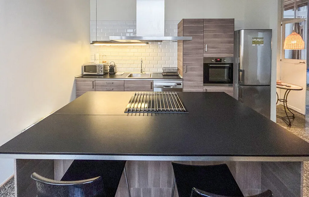 Una cocina moderna con una amplia isla oscura y electrodomésticos de acero inoxidable.