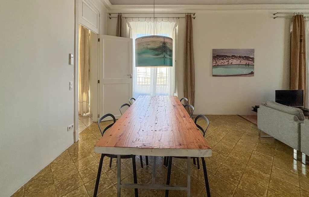 Un comedor con una mesa larga de madera y sillas junto a una ventana luminosa.