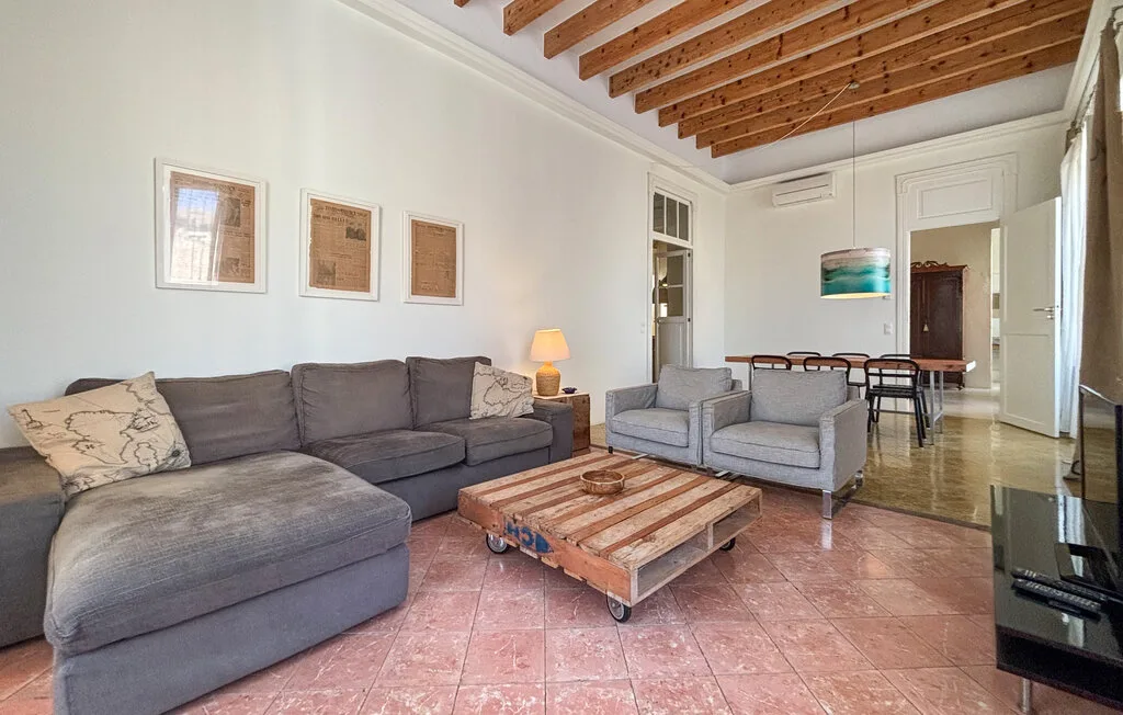 Una sala de estar con asientos grises y una mesa de centro de madera bajo vigas vistas.