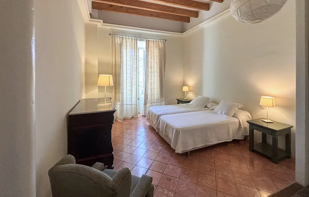 Un dormitorio con dos camas, mesitas de noche y una ventana con cortinas.