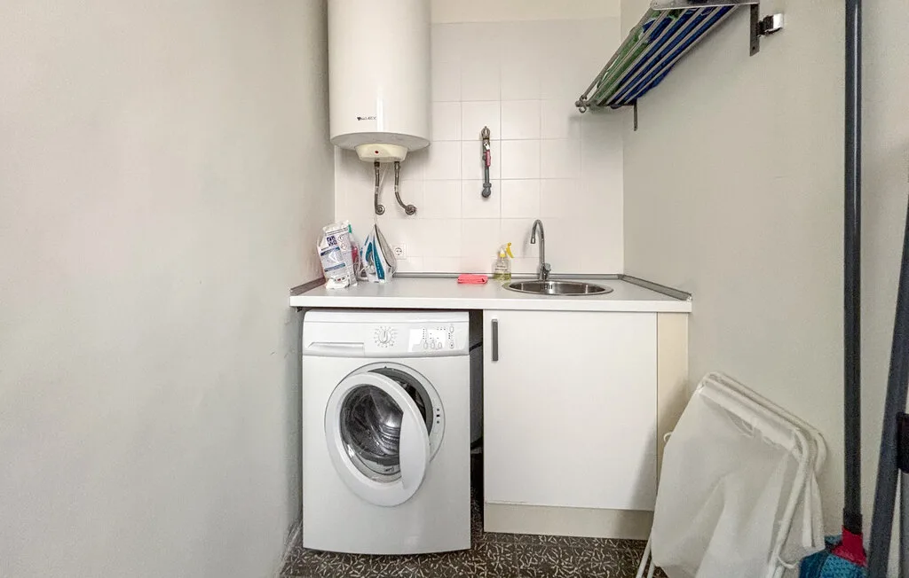 Un cuarto de servicio compacto con una lavadora bajo una encimera y un fregadero.