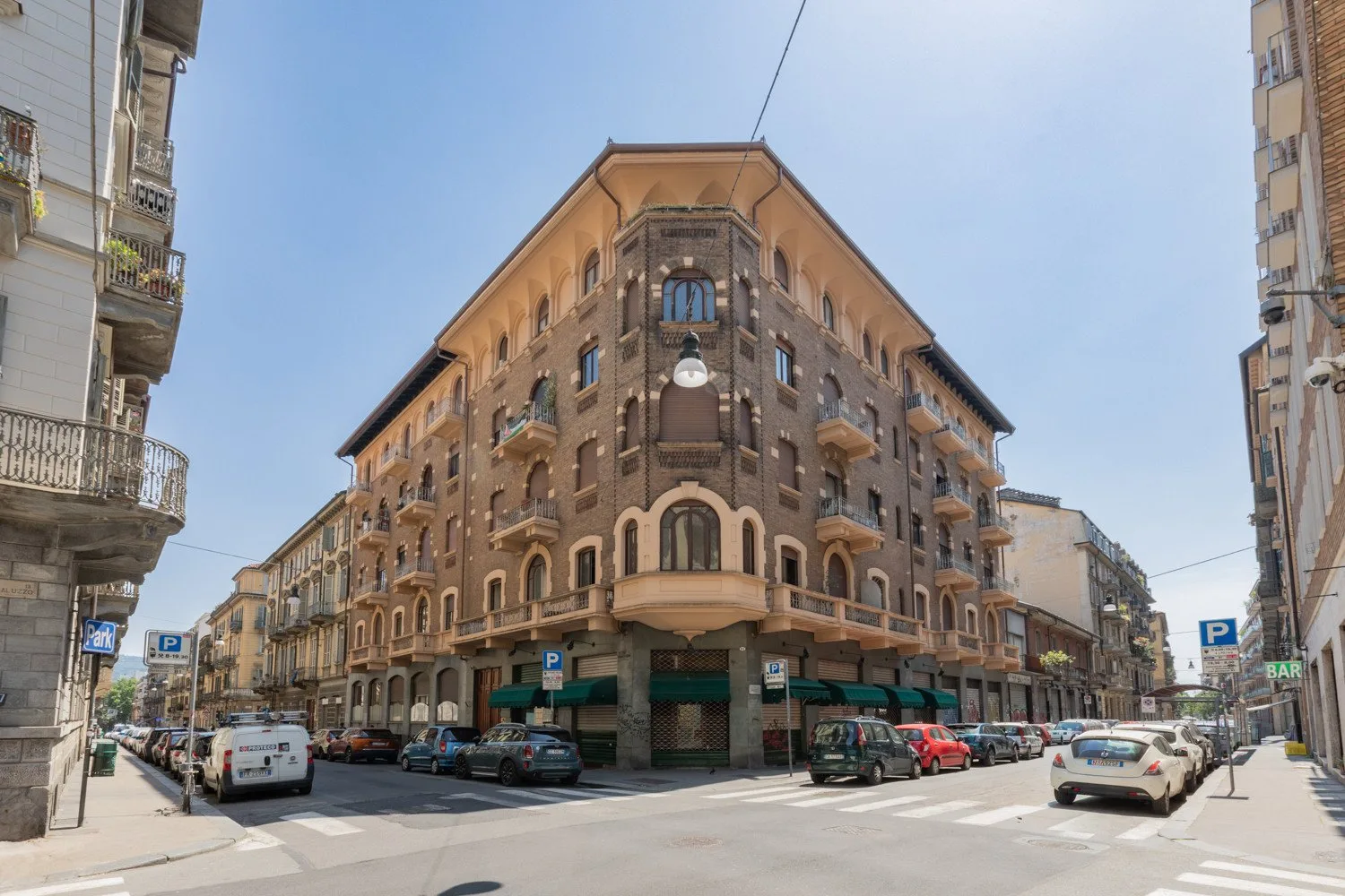 Una intersección con un gran edificio en esquina y coches estacionados.