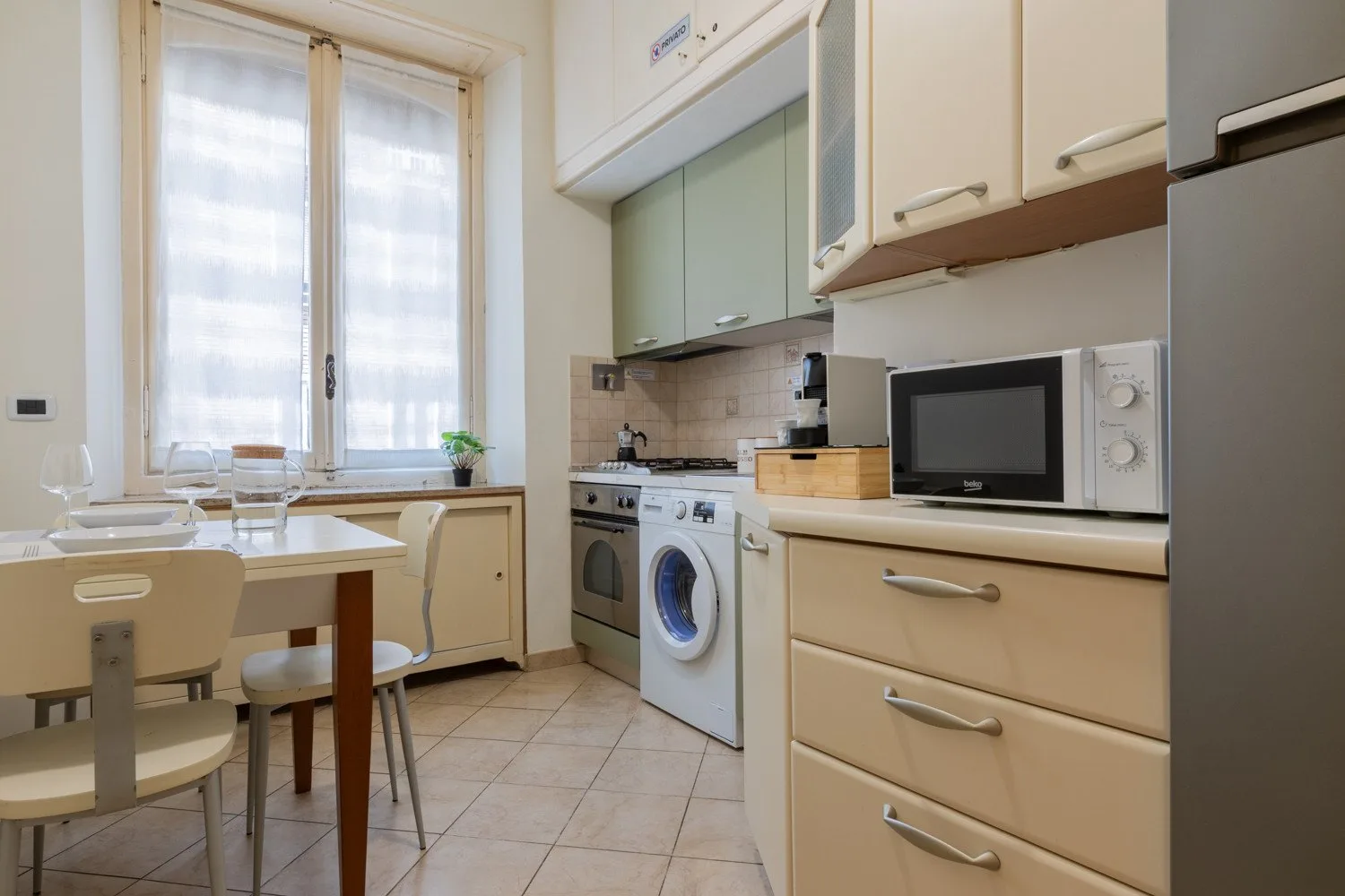 Una cocina compacta con una mesa de comedor junto a una ventana grande.