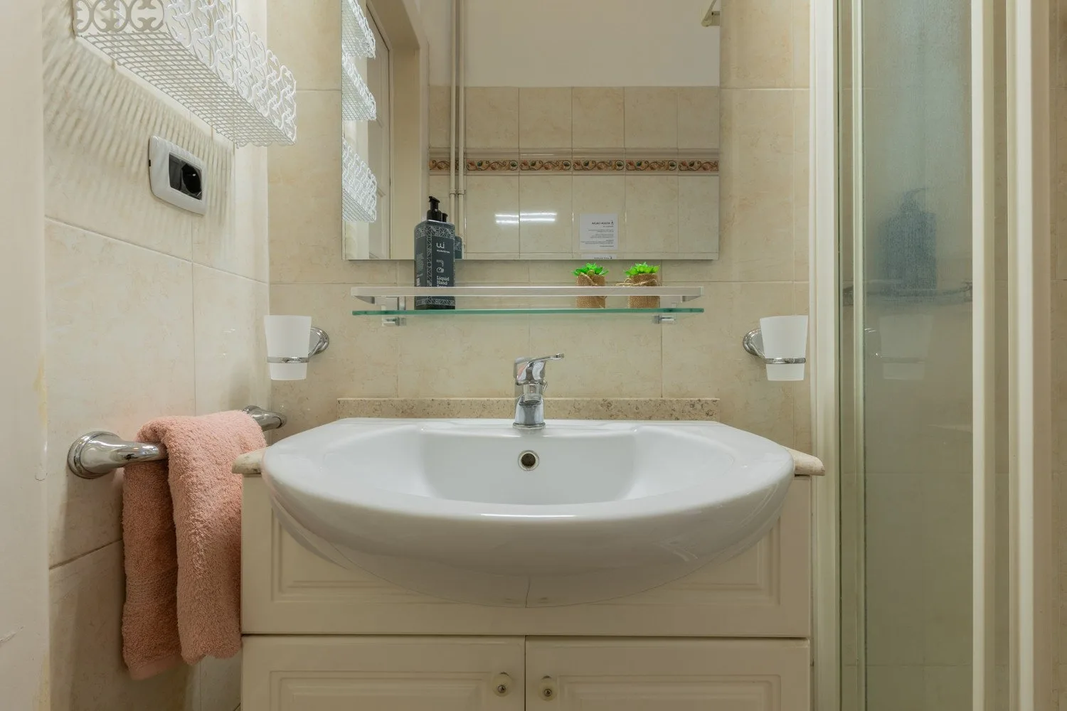 Un lavabo de baño está situado debajo de un espejo de pared.