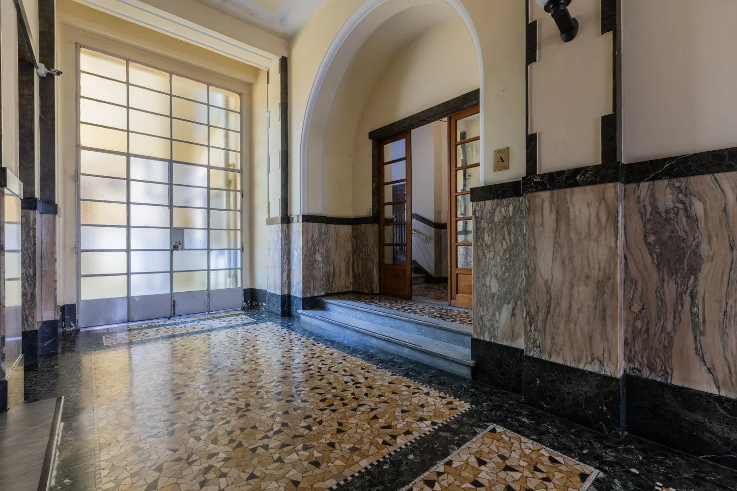 Un recibidor interior con suelo estampado, una ventana grande y un arco.