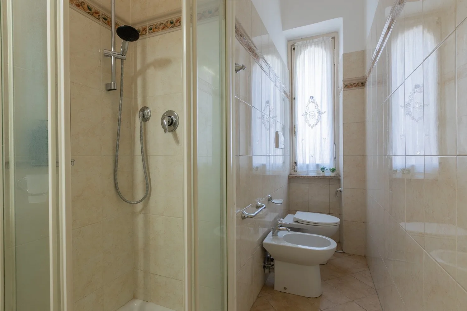 Un baño alicatado con ducha, lavabo y ventana.