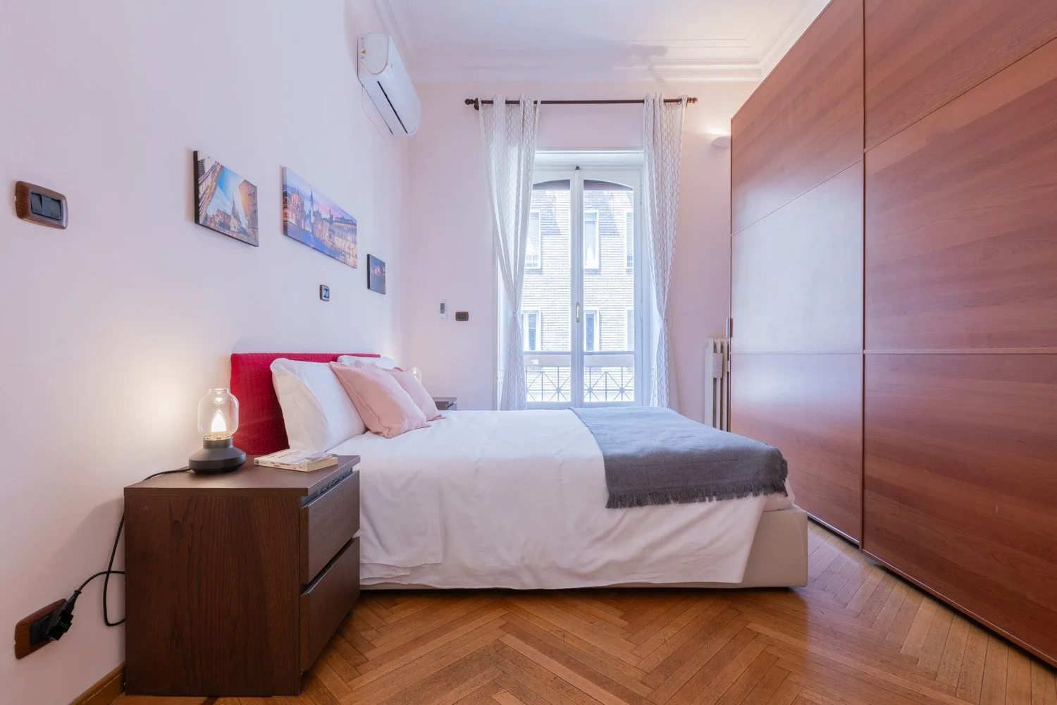 Un dormitorio con una cama ordenada junto a una ventana grande.