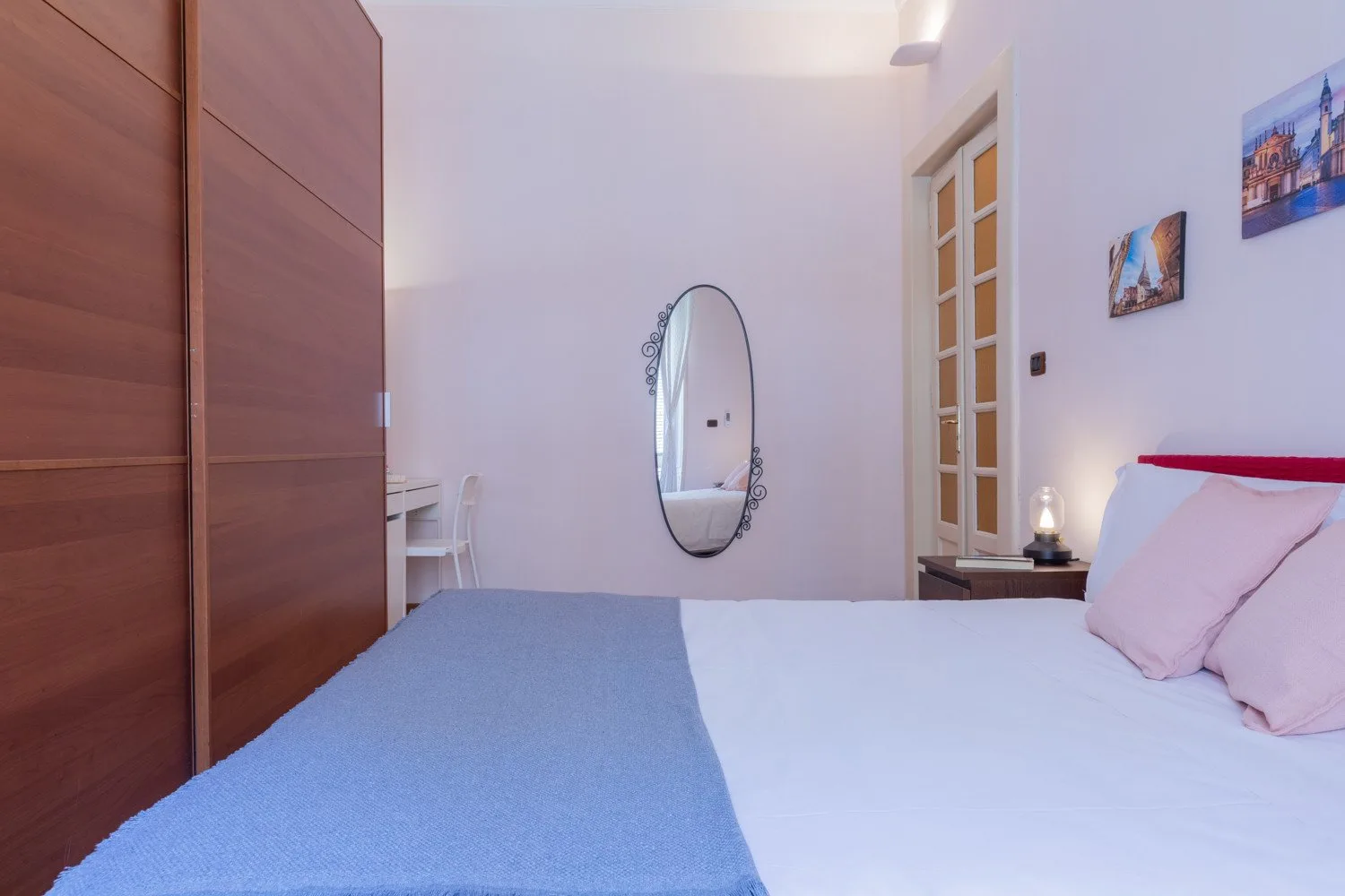 Un dormitorio con una cama, un espejo ovalado y un gran armario de madera.