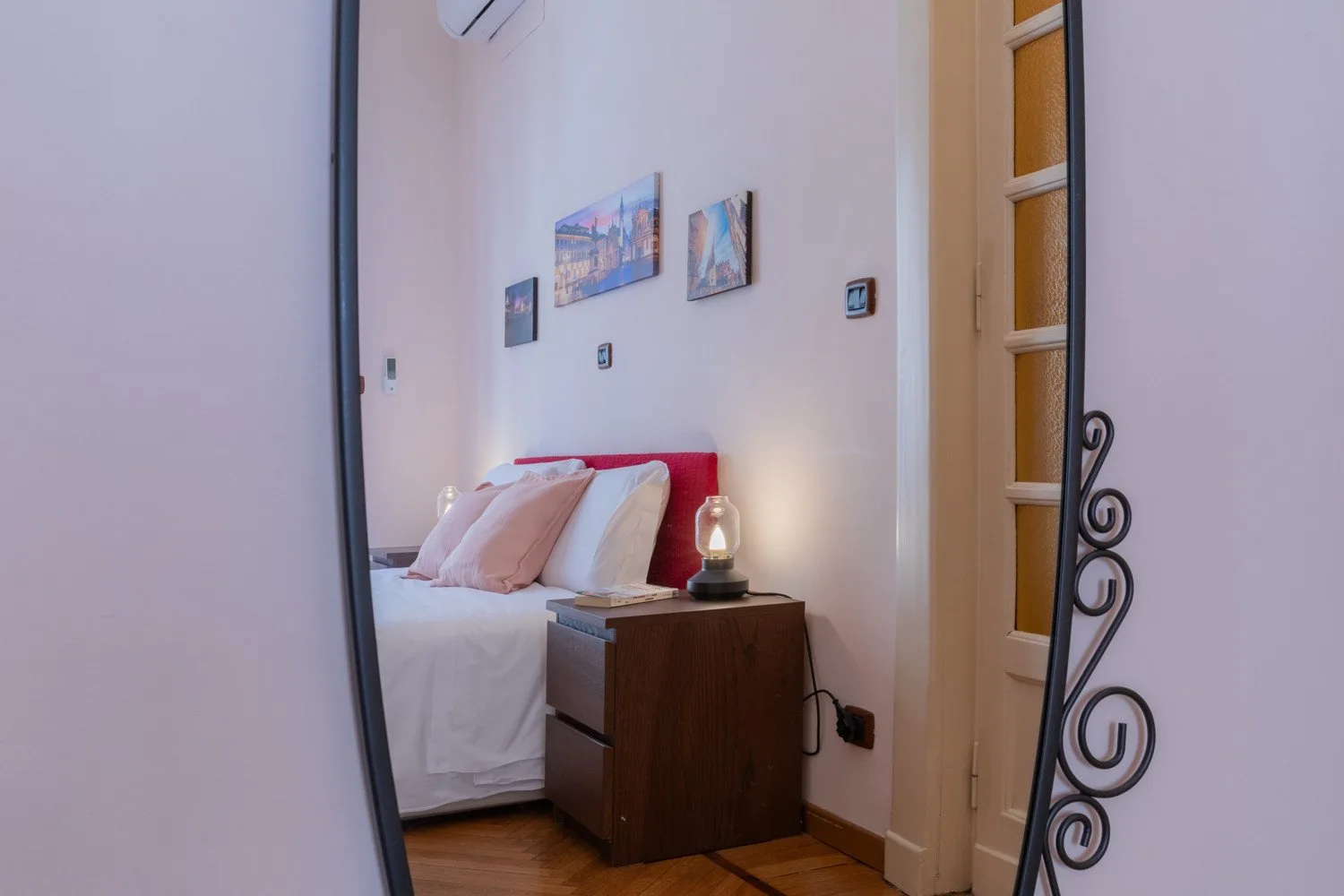 Un dormitorio con una cama, una mesita de noche y cuadros en la pared.