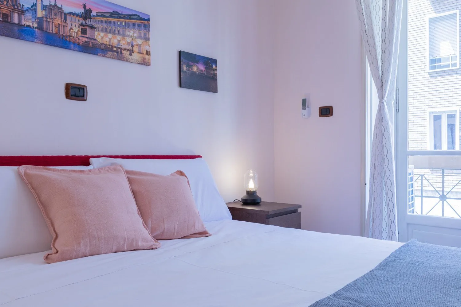 Un dormitorio con una cama bien hecha, almohadas claras y una mesa de noche.