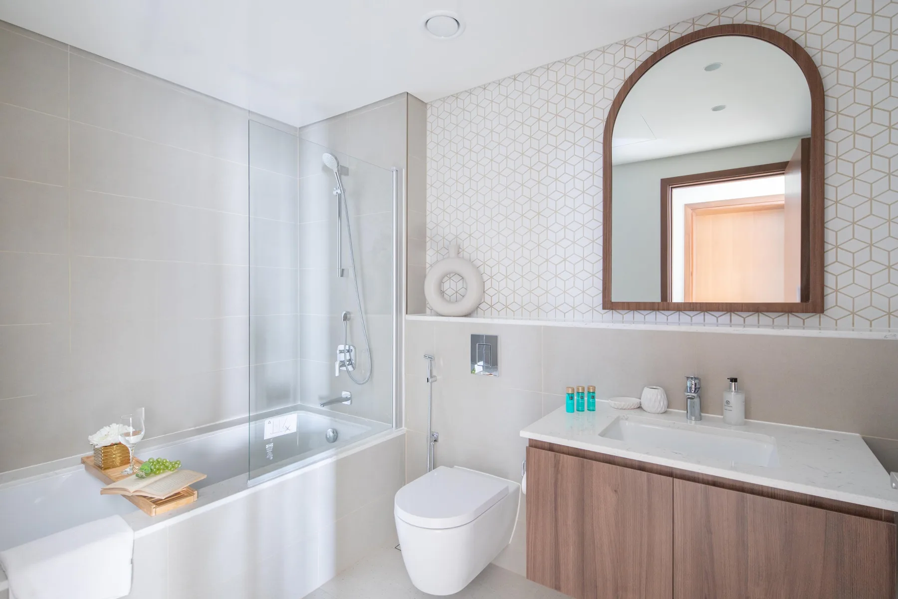 Un baño luminoso con bañera, ducha y lavabo con mueble de madera.