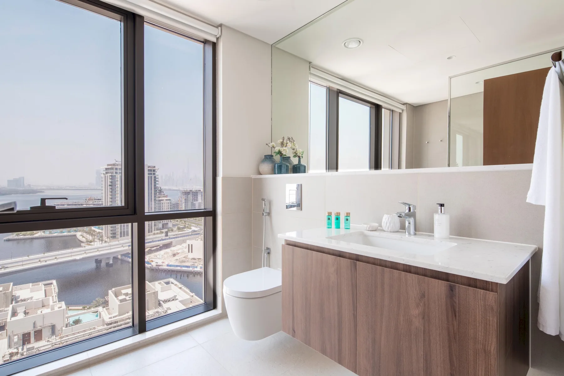 Un baño luminoso con un amplio tocador y grandes ventanas con vistas a la ciudad.