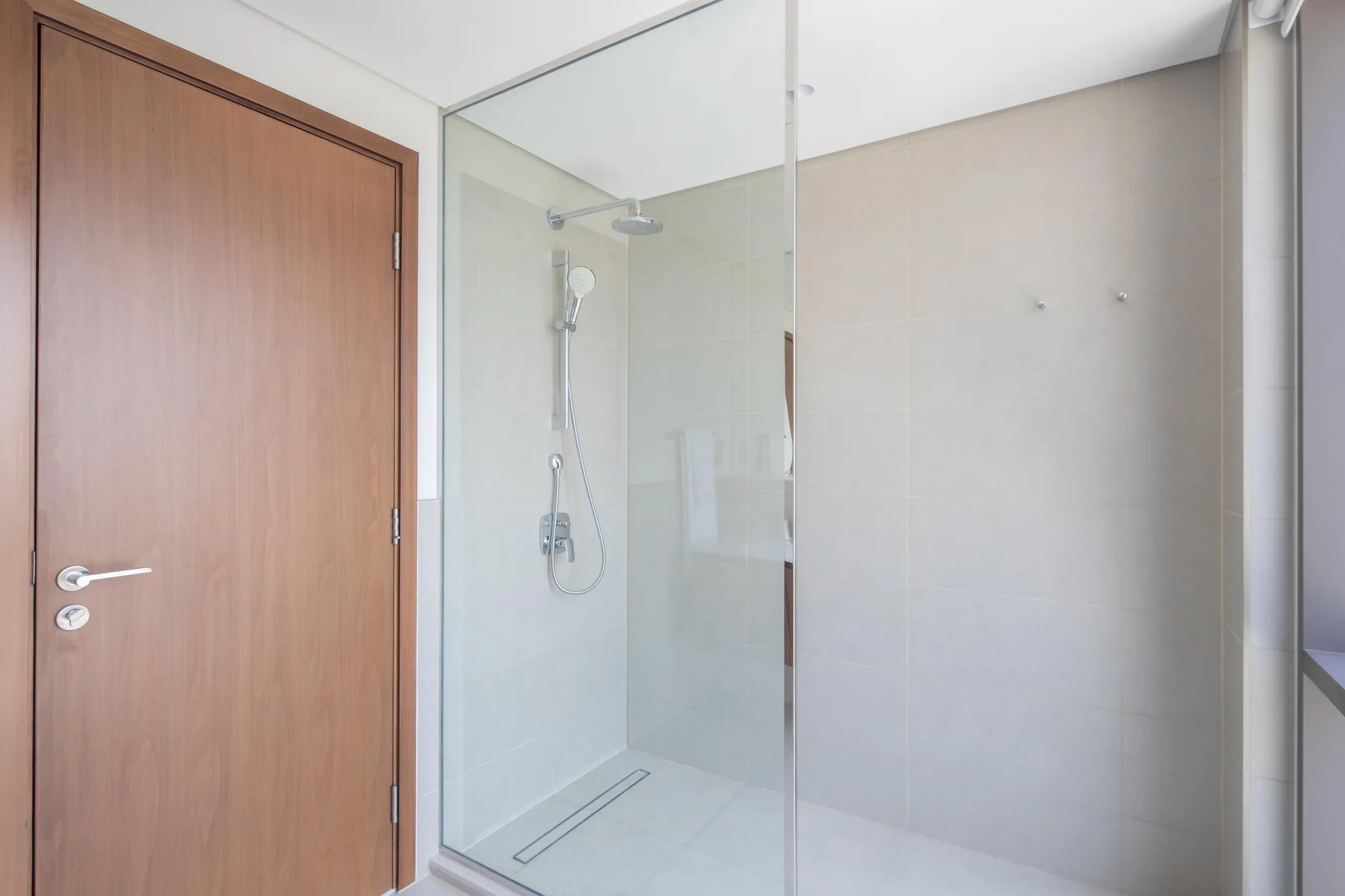 Un baño con una ducha de vidrio y una puerta de madera.