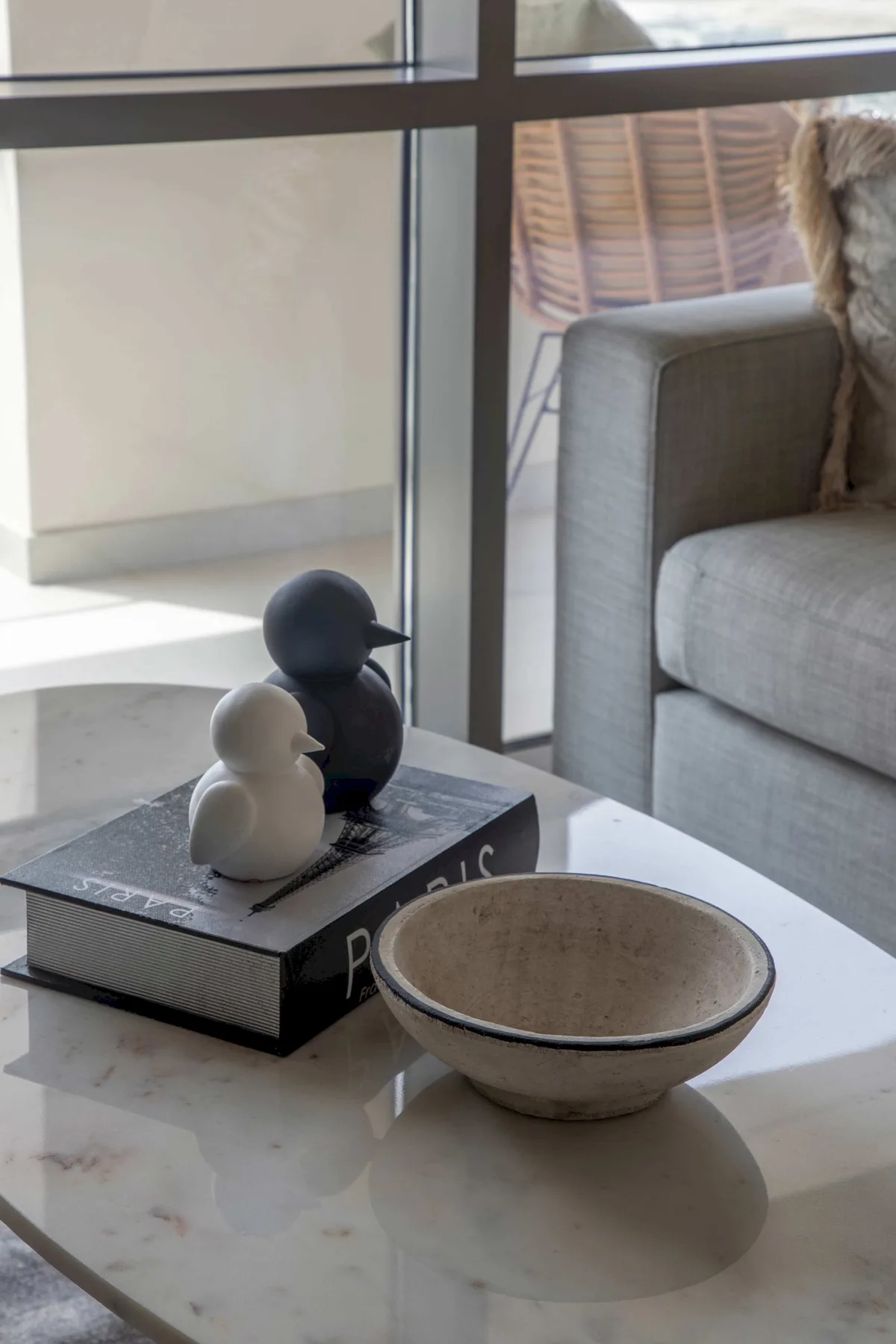 Una zona de estar con figuras de aves y un cuenco sobre una mesa de centro.