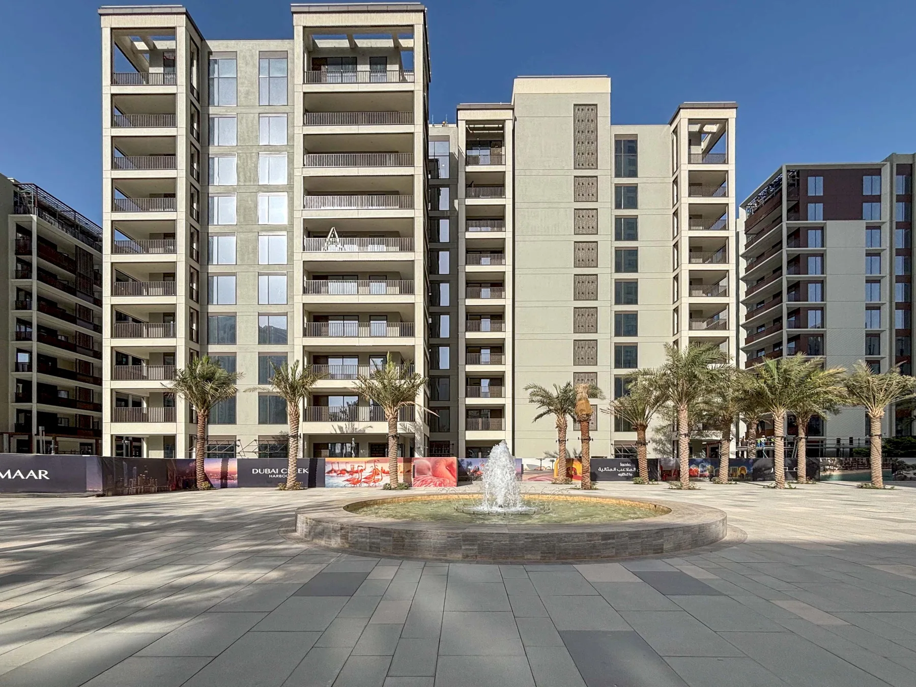 Una plaza pavimentada con una fuente está frente a varios edificios de apartamentos.