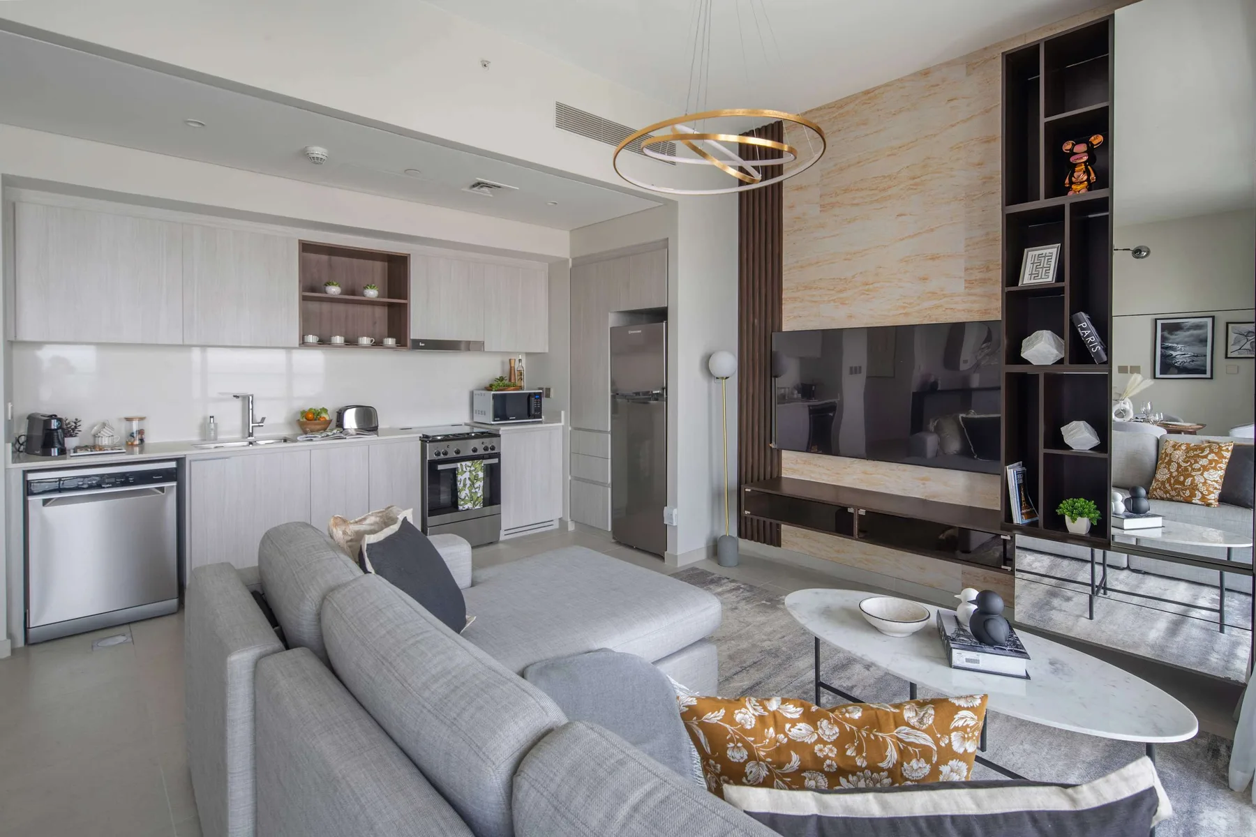 A modern living room with a gray seating area and an open kitchen.