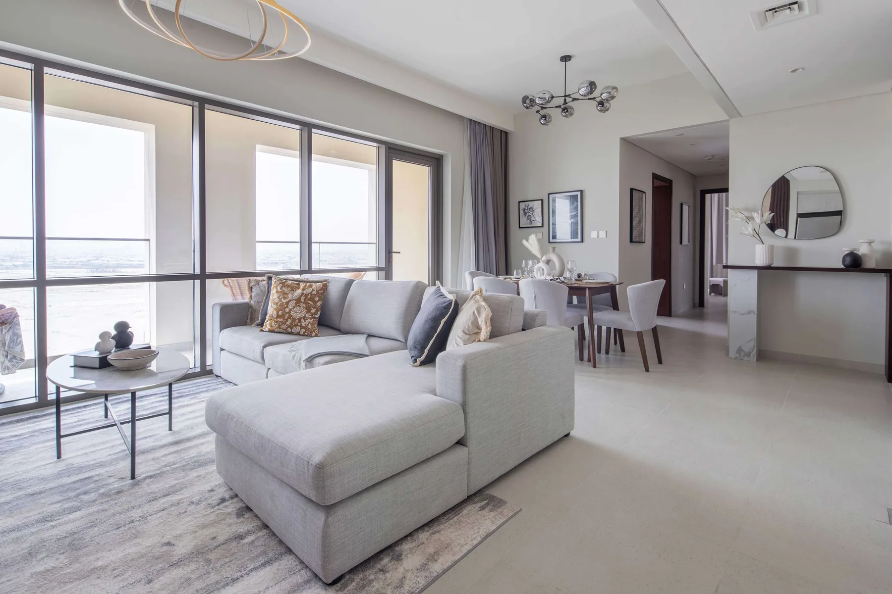 A bright living room with a sectional seating area beside large windows.