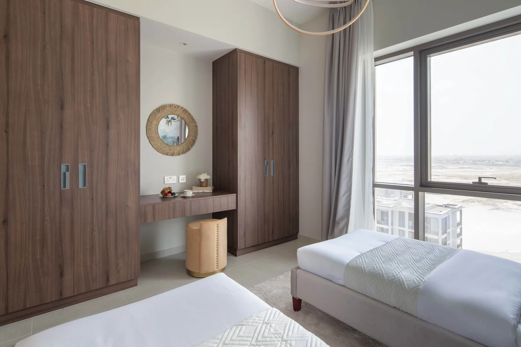 Un dormitorio luminoso con dos camas, armarios de madera y una ventana grande.