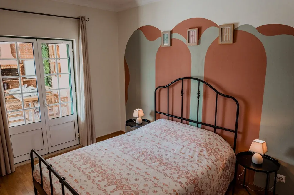 Un dormitorio con una cama estampada y un diseño de arcos pintado en la pared.