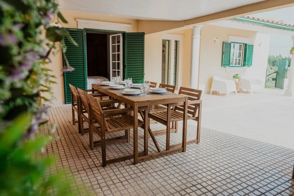Un patio cubierto con una mesa de comedor de madera y sillas.