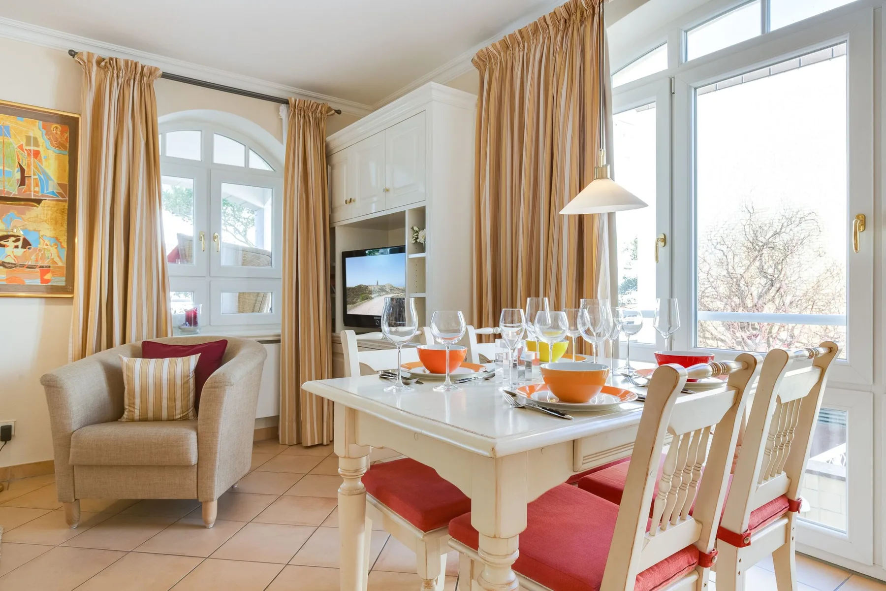 Un comedor luminoso con la mesa puesta junto a grandes ventanas y un asiento acolchado.