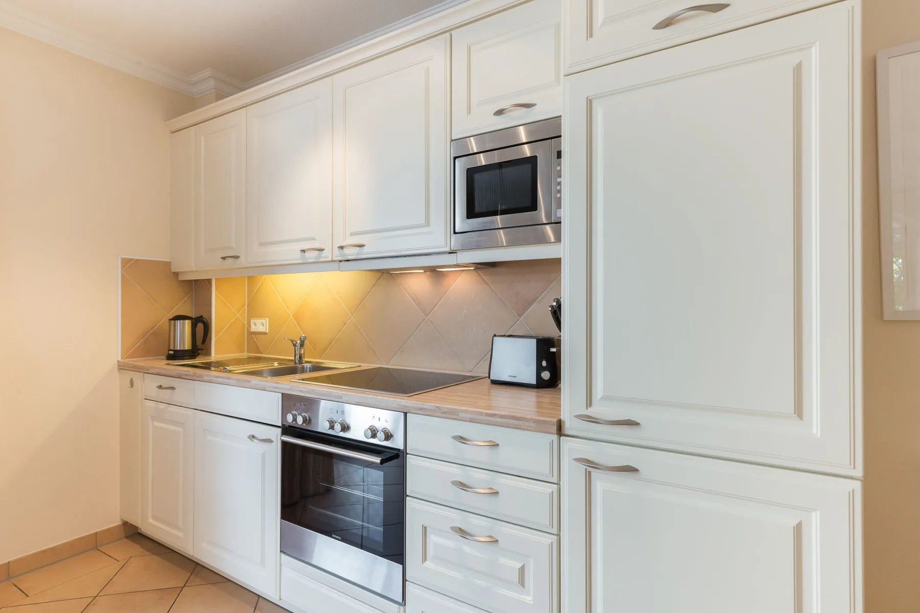 Una cocina luminosa con gabinetes blancos, una encimera y electrodomésticos integrados.