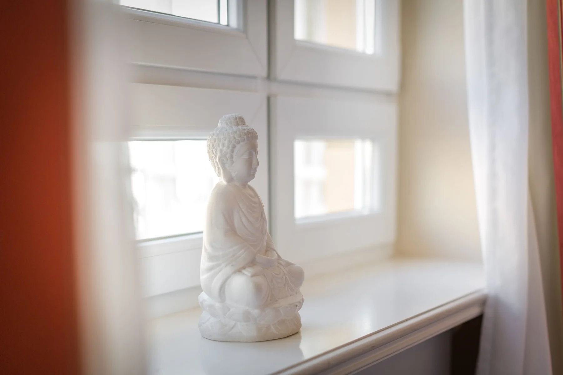 Una pequeña estatua de Buda está sobre un alféizar luminoso.