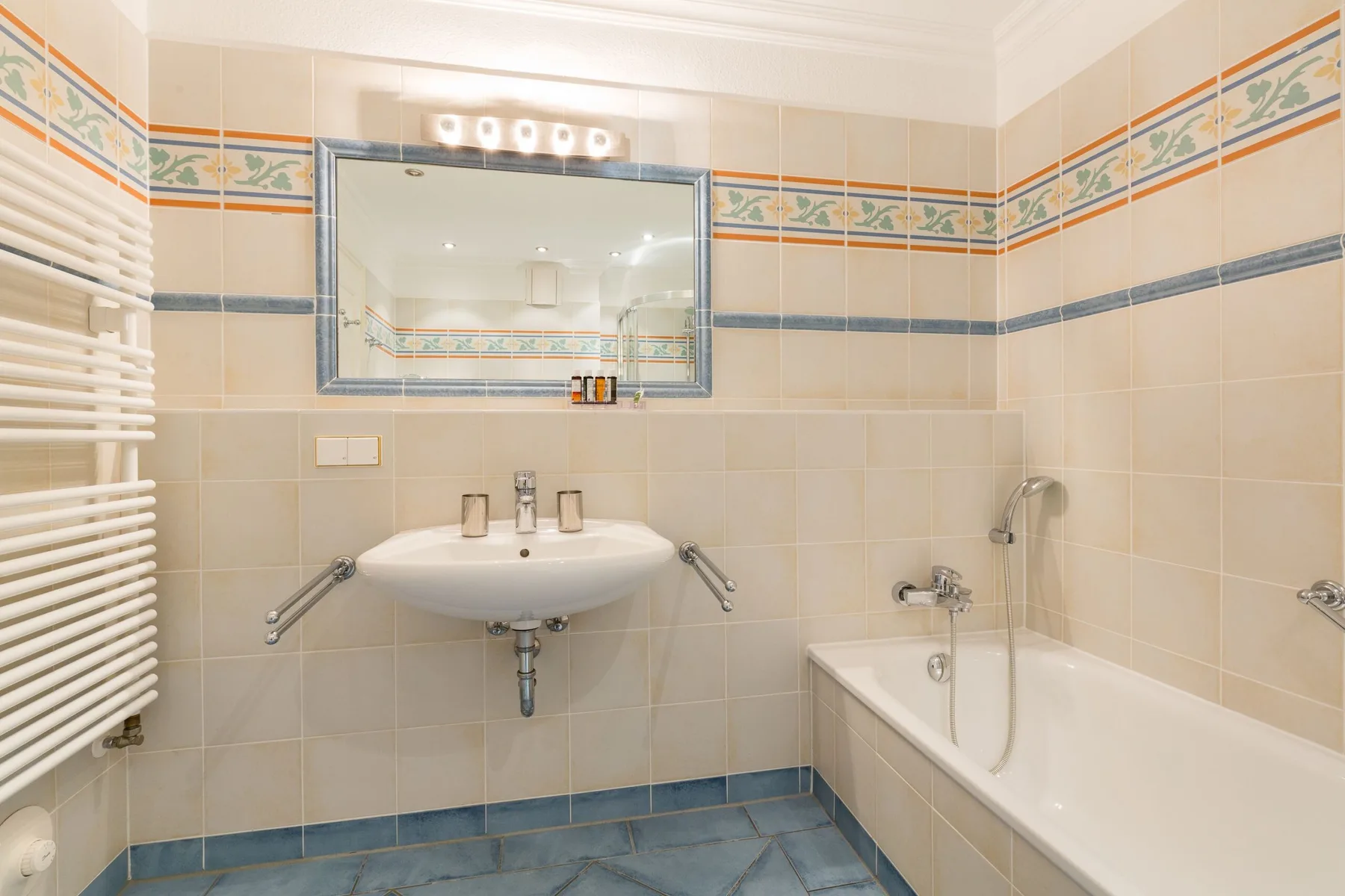 Un baño con azulejos, lavabo de pared y bañera.