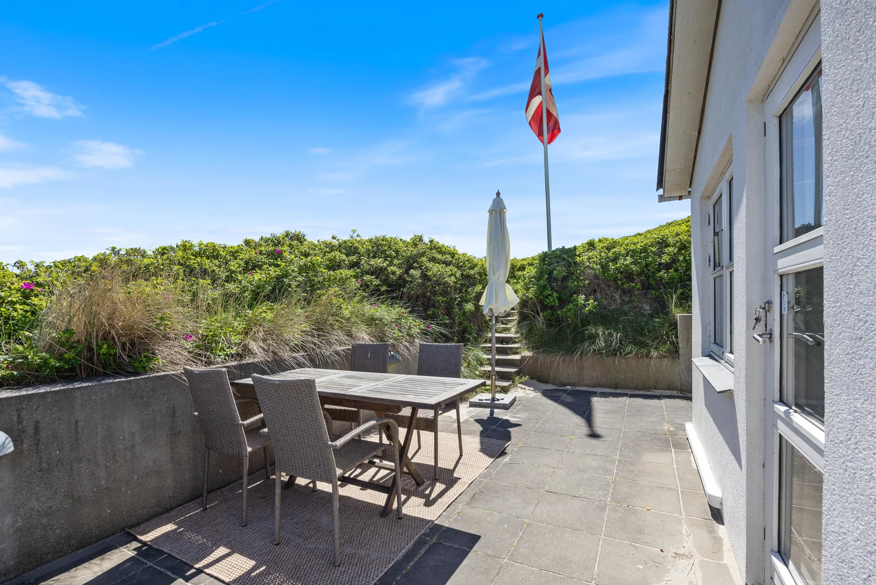 Un patio exterior con una mesa de comedor y asientos junto a la casa.