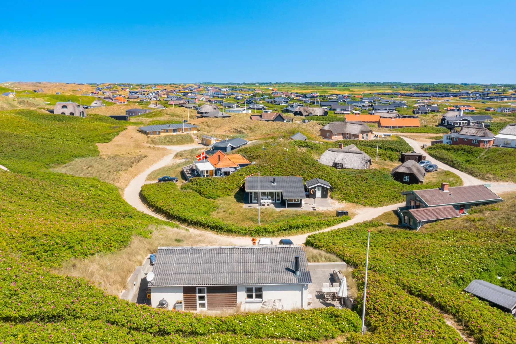 Vista aérea de una zona residencial costera con caminos sinuosos y casas dispersas.