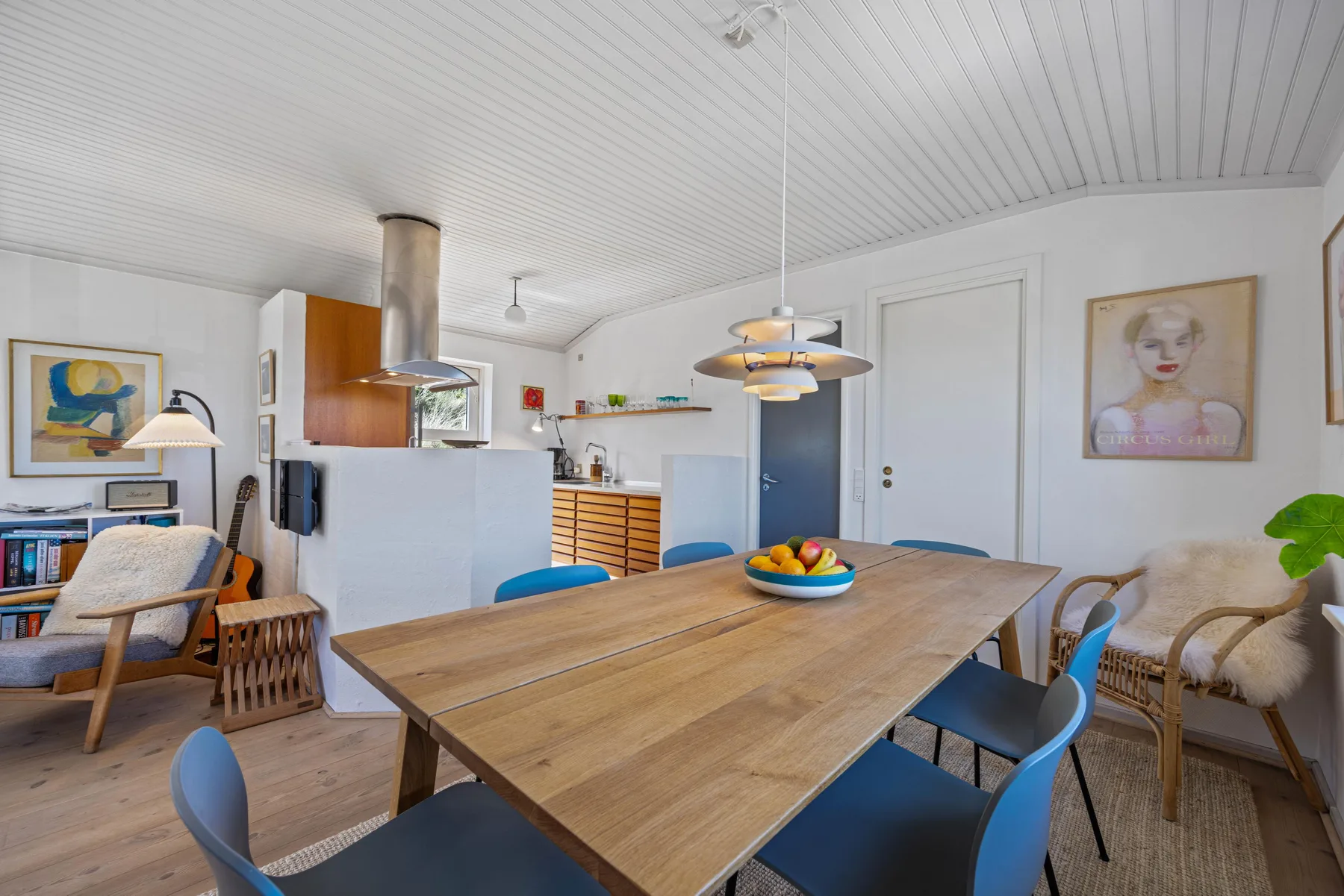 Comedor con mesa de madera y asientos azules junto a la cocina.