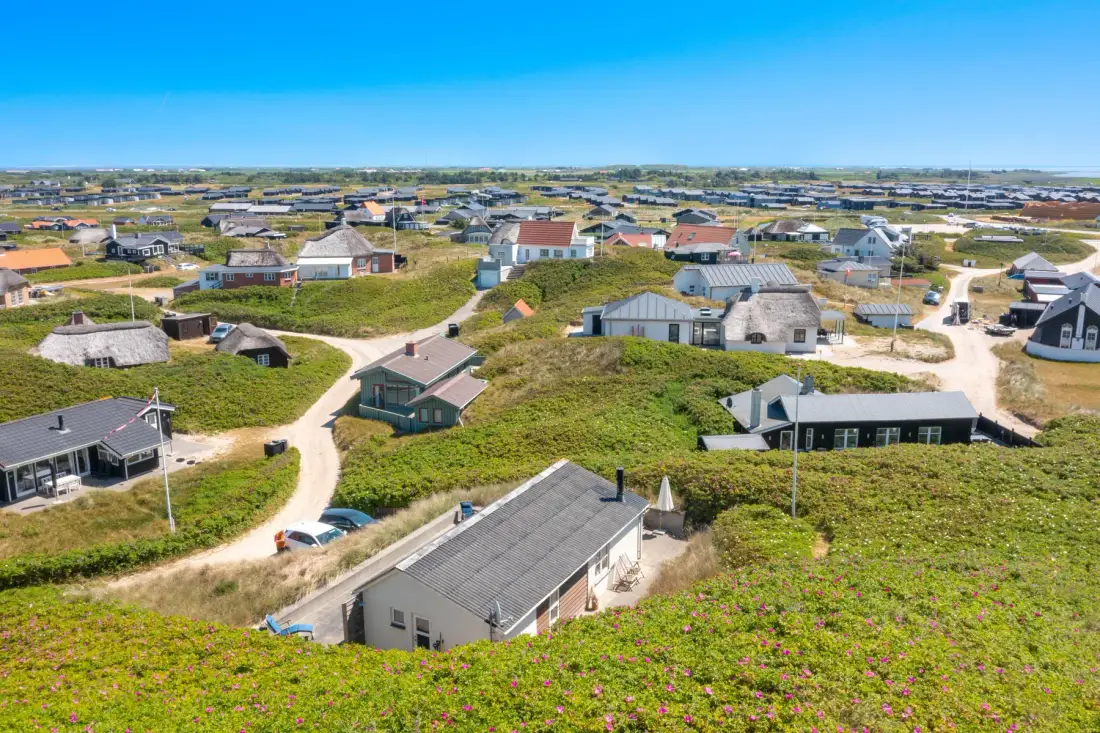 Vista aérea de casas entre dunas bajas cubiertas de hierba.