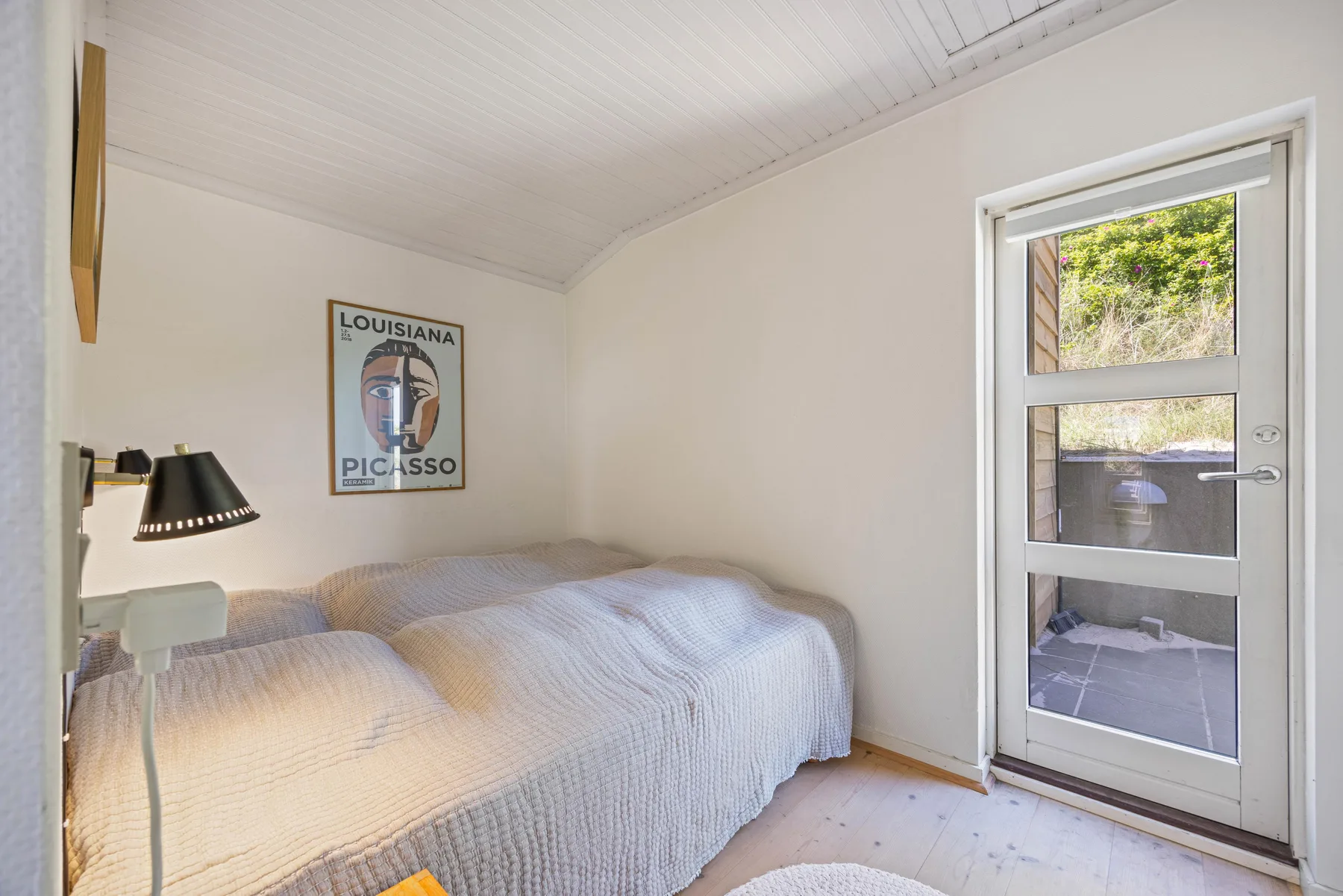 Dormitorio con camas junto a una puerta con paneles de vidrio.