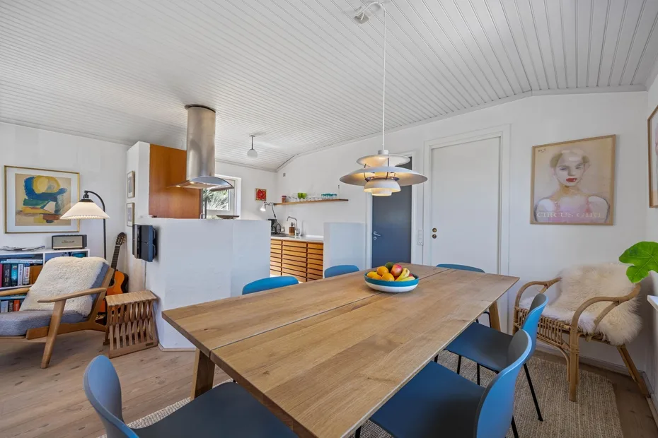 Comedor con una mesa larga de madera, asientos azules y lámparas colgantes.
