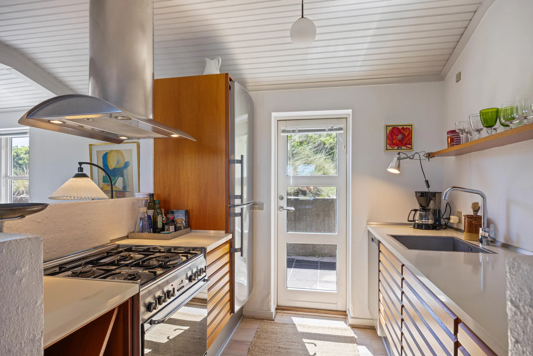 Una cocina luminosa con una cocina grande, una encimera y una puerta acristalada.