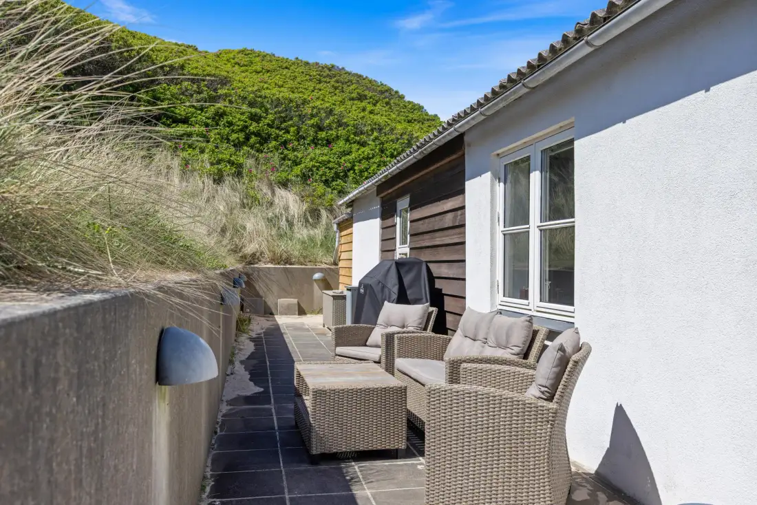 Un patio exterior con asientos de mimbre junto a la casa.