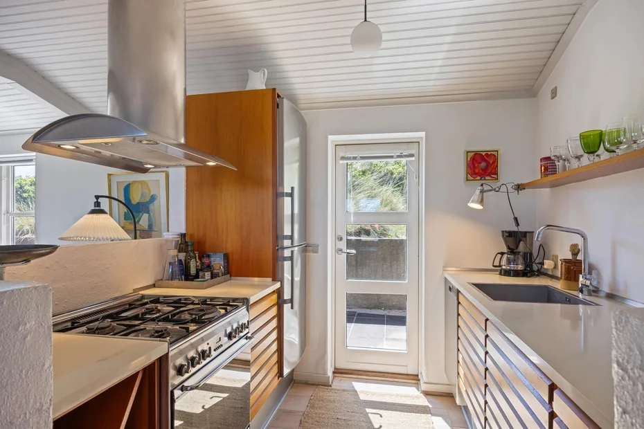 Una cocina luminosa con una estufa central y una puerta con paneles de vidrio.